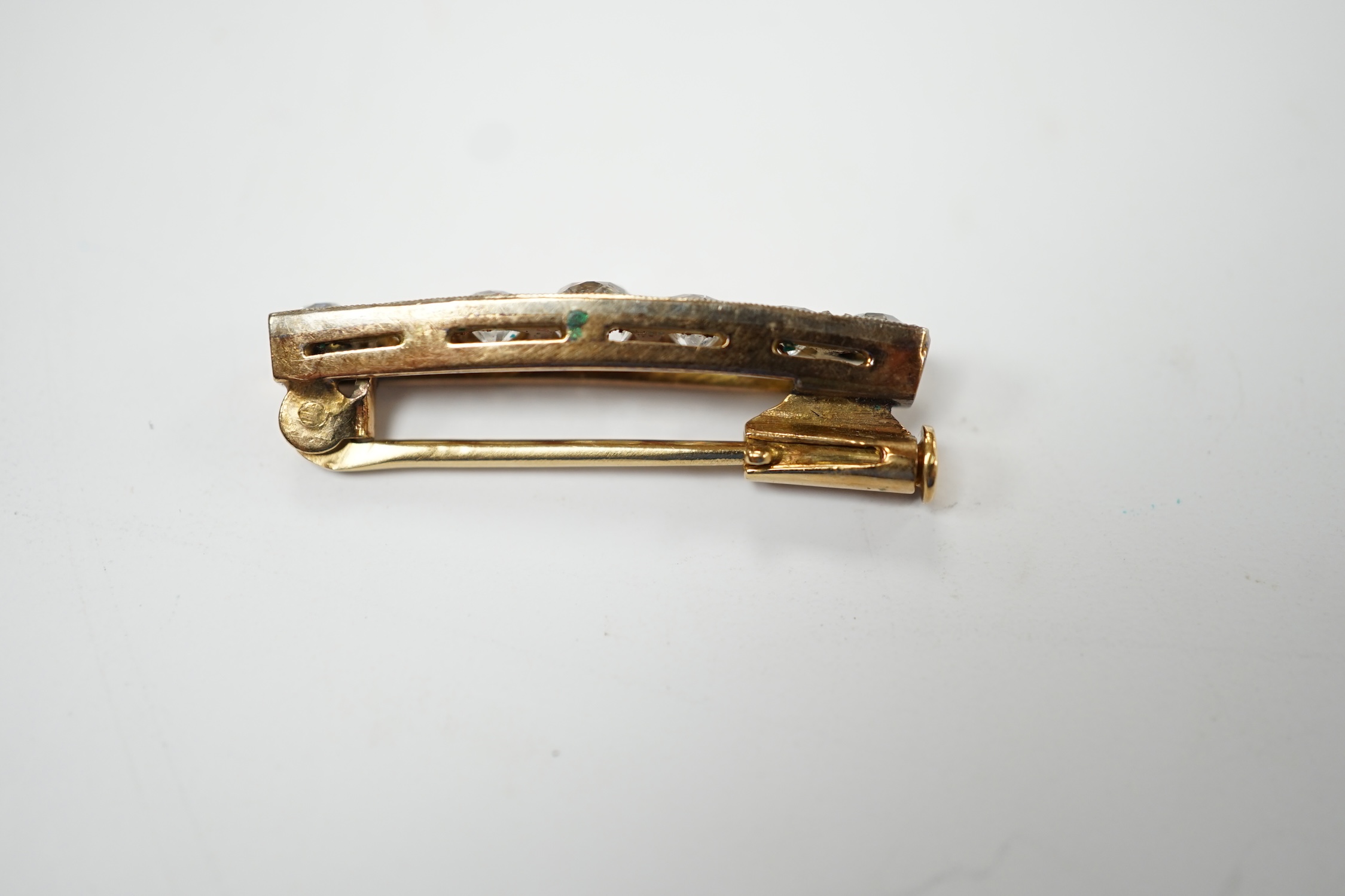 A small yellow metal and seven stone graduated diamond set bar brooch, 28mm, gross weight 3.9 grams (two cracks to one stone). Fair condition.